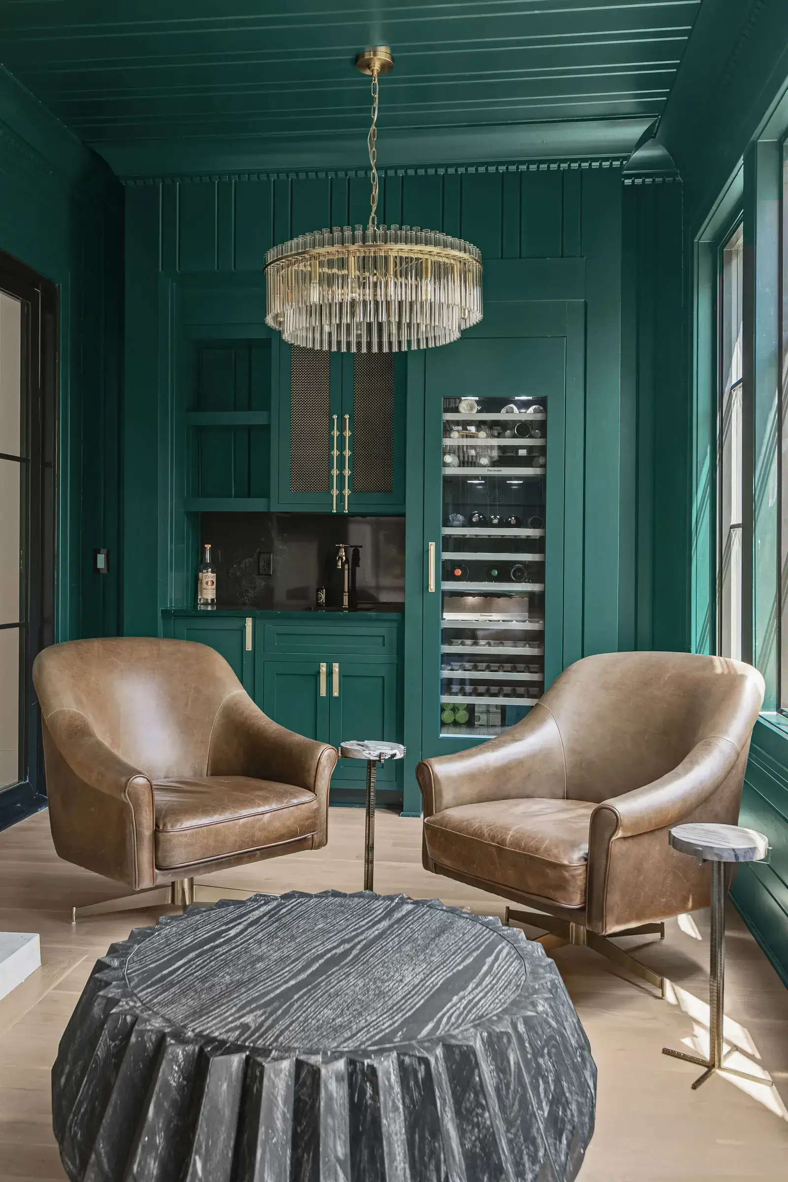 Luxury interior with green walls, chandelier, and leather chairs